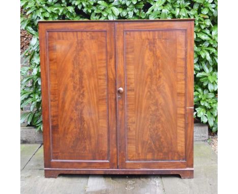 An Early 19th Century Mahogany Side Cabinet with two crossbanded doors enclosing sliding trays and hanging, raised upon brack