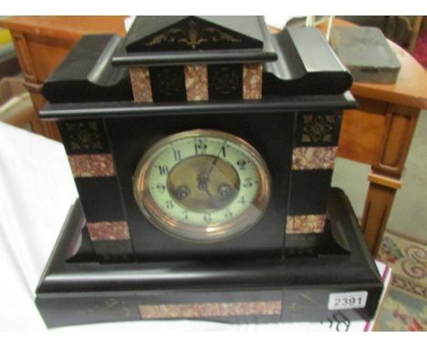 An Edwardian black slate mantel clock with pink marble embelishments.