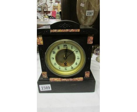 An Edwardian black slate mantel clock with pink marble embelishments.