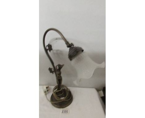 A metal figural reading lamp with glass shade.