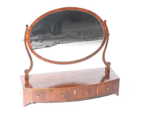 A Georgian mahogany dressing table mirrorWith an oval plate supported on curvilinear supports above a bowfront plinth base wi