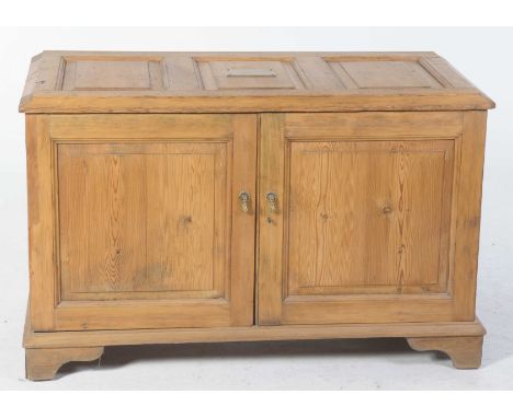An early 20th Century pine cupboardHaving a three panel invert moulded top above a pair of cupboard doors enclosing an arrang