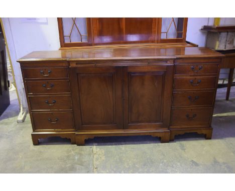 A reproduction mahogany breakfront sideboardHaving a central sliding tray above a pair of cupboard doors flanked by four draw