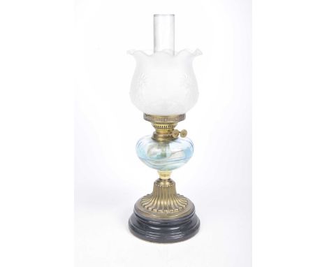 A late Victorian oil lampThe black stepped ceramic base extending to a fluted gilt metal stem with blue pressed glass oil rec