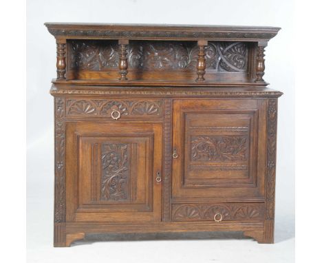 A late Victorian carved oak buffet sideboardThe raised back with a moulded cornice carved with repeating half flower head rou