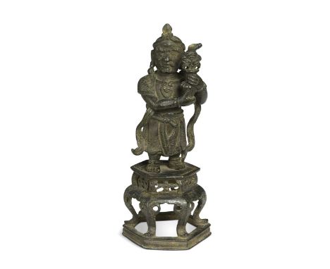 A Chinese bronze Daoist figure, Ming Dynasty (1368-1644), standing holding a vase (parts lacking) upon a six-legged table sta