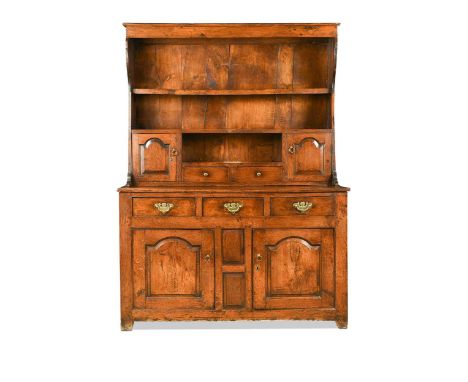 A Welsh elm and oak dresser, 18th century, the boarded plate rack with pair of fielded panel cupboard doors flanking two shor