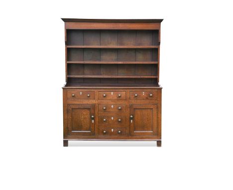 An oak dresser, 18th century, with boarded three shelf plate rack, the base with three short drawers over three faux drawers 