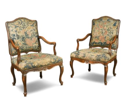 A pair of Louis XV walnut armchairs, the cartouche shaped back and seat upholstered in a period floral needlepoint tapestry, 