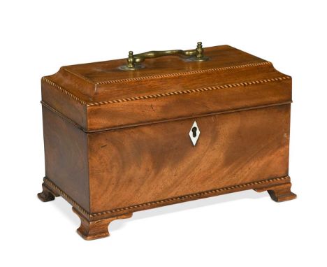 A George III mahogany tea caddy, the sarcophagus hinged cover with chevron stringing and brass carrying handle, raised on sha