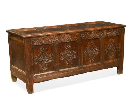 An oak panelled coffer, 18th century, the panelled hinged lid over a carved top rail with repeating S-curl decoration, inscri
