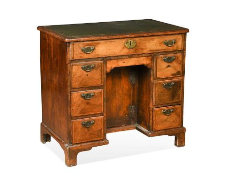 A walnut kneehole desk, 18th century, with one long over six short drawers around a central recessed cupboard door on bracket