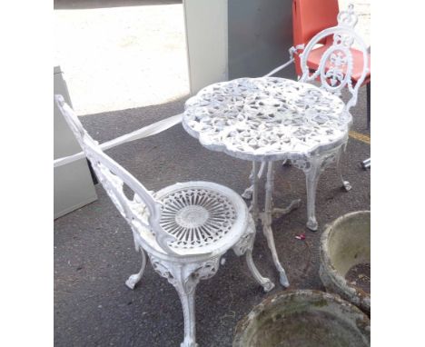 A vintage cast metal circular garden table with two chairs