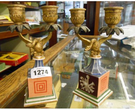 A paie of ormolu twin branch candlesticks in the form of swans, set on decorative ceramic pedestal bases