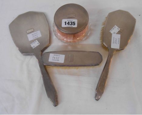 A four piece silver mounted dressing table set comprising a powder jar with internal mirror to lid, hand mirror and two brush