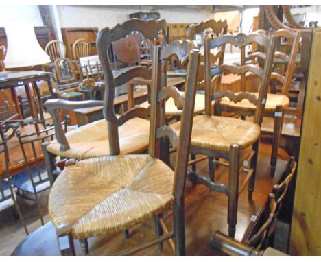 A set of eight French oak framed ladder back dining chairs with woven rush seats and moulded front supports, comprising six s
