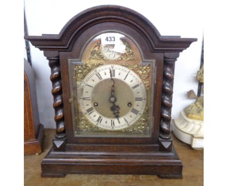 A early 20th Century stained oak break dome top cased table clock with decorative dial, flanking barley twist columns and Jun