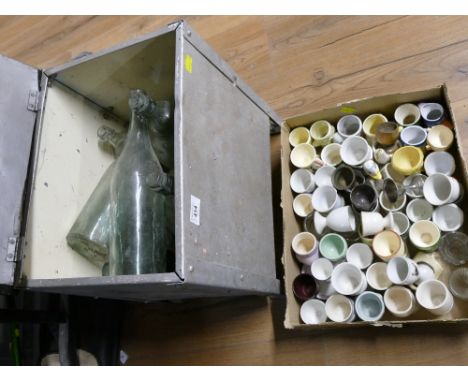 Metal storage trunk containing vintage glass bottles and egg cups 