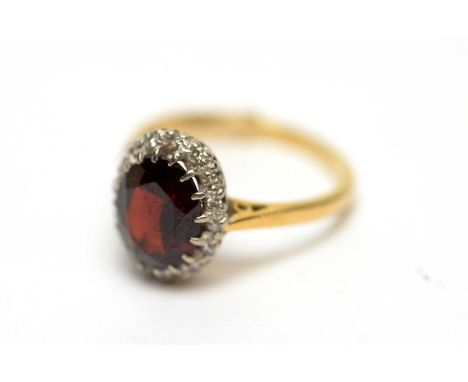 A garnet and diamond cluster ring, on yellow metal shank stamped '18ct', ring size N, 4.2g gross. 