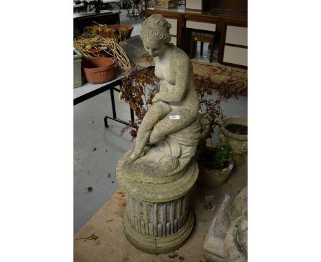 A 20th Century stone composite garden ornament, modelled as a figure of a nude lady upon a pillar base, 104cms high overall.