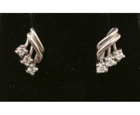 A pair of diamond earrings, each set with three brilliant cut diamonds estimated to weigh of a total of 0.20carat, in white m