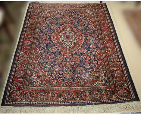 A Ghazvim carpet, the central floral medallion within foliate borders, in shades of red and blue, 190 x 137cms wide. 