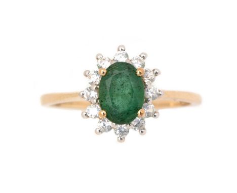 An emerald and white stone ring, the oval facet cut emerald measuring 7.0 x 5.0 x 3.9mm, surrounded by white stones, on 9ct y