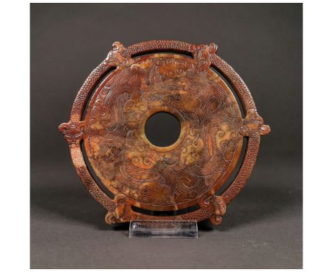 A brown colored Archaic jade bi with the typical circular shape; six dragon heads carved on the outermost part of the disc; t