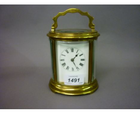 Early 20th Century oval gilt brass carriage clock, the enamel dial with Roman numerals, the two train movement striking on a 