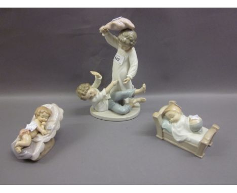 Group of three Nao figures, including two children having a pillow fight and two children in cots