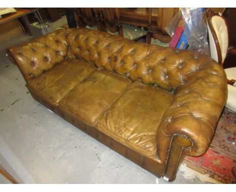 Tan leather button upholstered three seater Chesterfield sofa raised on bun feet