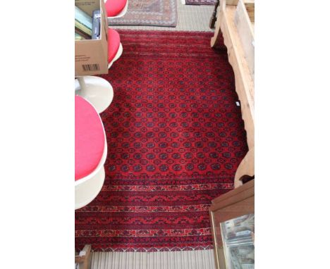 A PIGEON RED GROUND WOVEN WOOLEN CARPET with a busy geometric central field and multi-guard borders 