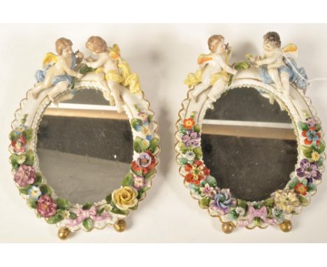 A pair of early 20th century German Sitzendorf porcelain cherub and floral encrusted barbola easel mirrors. Each with winged 