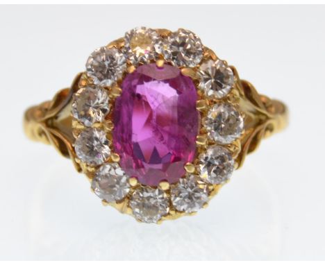 An 18ct gold ruby and diamond cluster ring.The ring having a central cushion cut natural ruby surrounded by a halo of round t