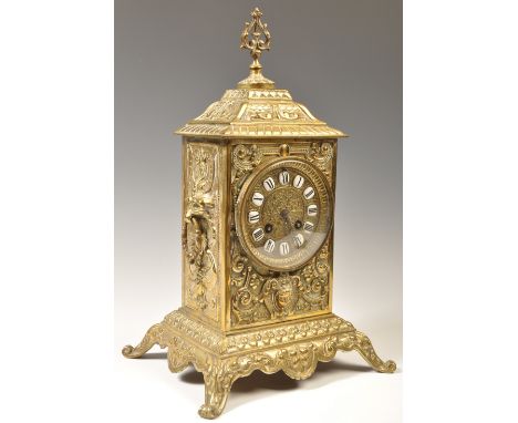 A 19th century French ornate brass mantel clock. The scrolled feet plinth with upright body having enamel roman numeral chapt