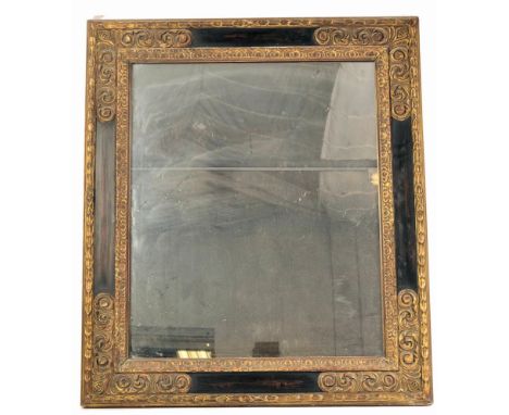 A late 19th century large gilt wood and gesso plaster worked carved wall mirror of ebonised cushion form having carved gilt d