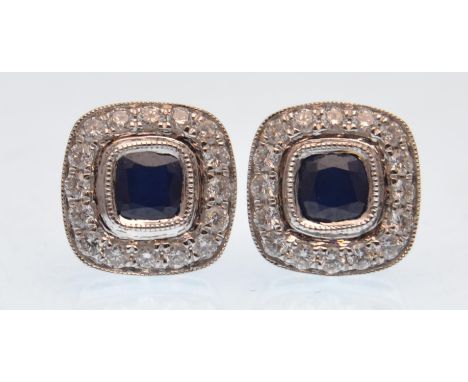 A pair of 18ct white gold, sapphire and diamond cluster earrings. The central cushion cut sapphires surrounded by a field of 