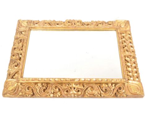 An early 19th century overmantel mirror having a florentine manner ornate gilt wood  frame carved with scrolls and flowering 