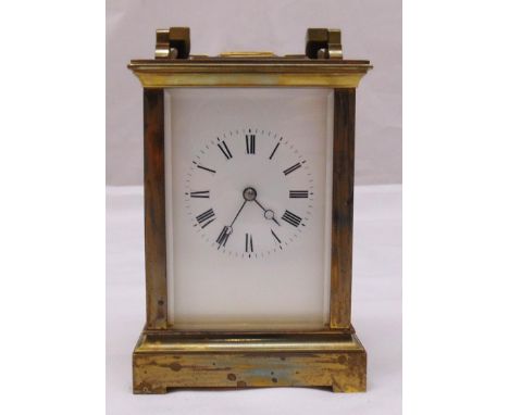 A brass chiming carriage clock, white enamel dial with Roman numerals and with swing handle