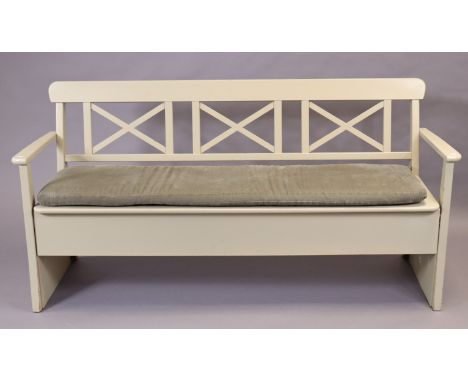 An off-white painted wooden bench with a trellis-type open back, loose cushion to the hinged box seat, &amp; on square tapere