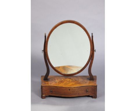 A Georgian mahogany oval swing dressing mirror on shaped supports &amp; serpentine-front box base fitted frieze drawer, on og