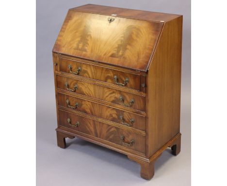 A reproduction mahogany small bureau with a fitted interior enclosed by a fall-front above four long graduated drawers; &amp;