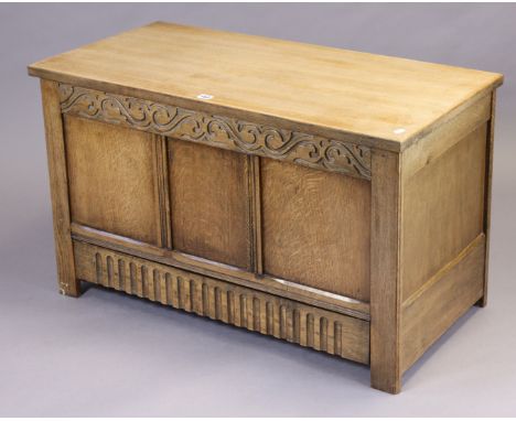 A light oak blanket box with a hinged lift-lid, &amp; with a carved panelled front, 93.5cm wide x 56.5cm high x 46.5cm deep. 