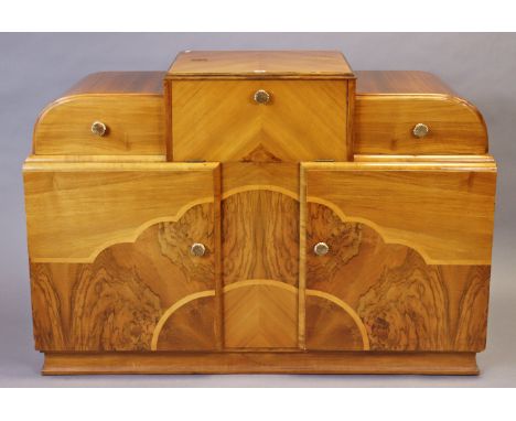 A mid-20th century burr-walnut drinks cabinet/sideboard enclosed by a hinged lift-lid &amp; fall-front to centre flanked by a