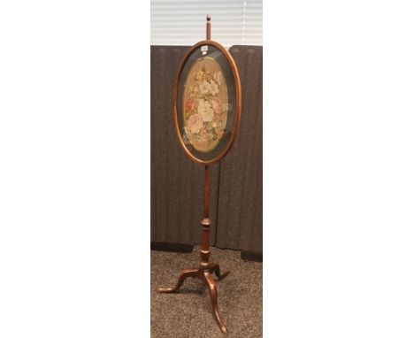 Antique Mahogany fire screen pole, the oval glass frame with needlework, raised on a pedestal and tripod base 