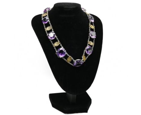An amethyst necklace, the eleven graduated round cuts set in white metal with metal flowermotifs between, the box catch set w