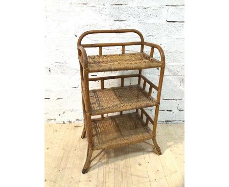 A cane and wicker open shelf with three tiers on splayed supports (89cm x 50cm x 37cm)