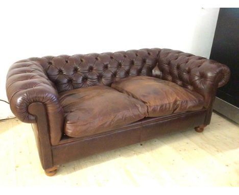 A Laura Ashley Chesterfield brown leather two seater sofa on bun feet, (69cm x 180cm x 103cm)