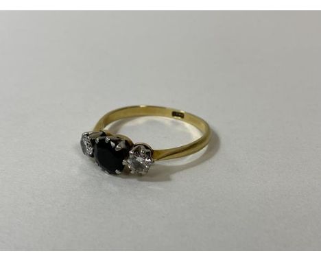 A sapphire and diamond ring marked 18k with central sapphire in claw setting flanked by two diamonds, size S, weighs 3.22 gra