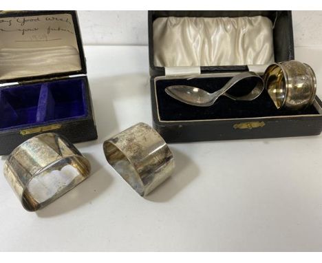 A pair of silver napkin rings, Birmingham, in original box, a silver napkin ring and baby spoon, Birmingham, combined weight 